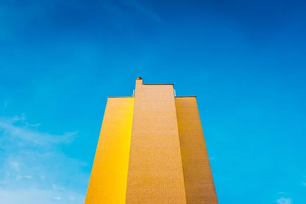 Hög tegelbyggnad, varm och gul vid solnedgången, med backgro — Stockfoto