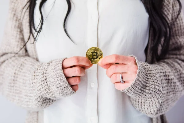 Mãos de mulher segurando uma moeda bitcoin . — Fotografia de Stock