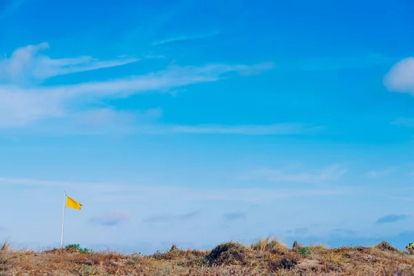 Bandeira de tecido amarelo acenando ao vento com o fundo de um c — Fotografia de Stock