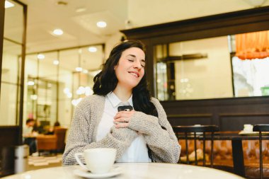 Cep telefonu için sevginin bir çağrı alırken bir kafede oturan kadın.