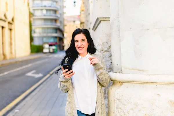Young woman laughing holding her smartphone, happy to receive good news. — Stock Photo, Image