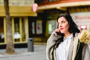 Orta yaşlı kadın, cep telefonundan telefon görüşmesi yapıyor.