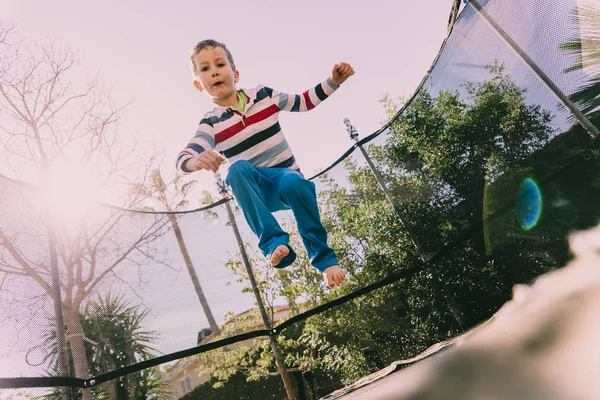 Niño de 5 años saltando en un trampolín haciendo ejercicio en el backyar —  Fotos de Stock