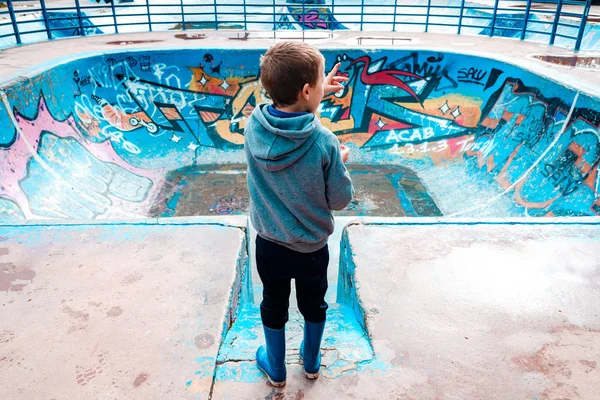 Gyermek csavarog egy elhagyatott korcsolyázó területen, kékre festve, — Stock Fotó