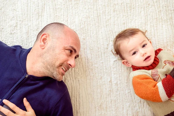 Father looks at his baby with affection and tenderness, lying to — Stock Photo, Image