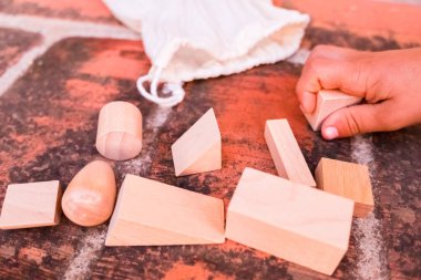 Çocuk farklı geometrik şekillerde tahta bloklarla oynuyor, 