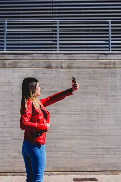Mujer joven fotografiándose con su teléfono para enviar un selfi — Foto de Stock