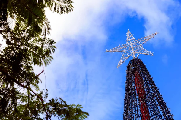 Una estrella sobre un árbol de Navidad, contra el cielo azul al aire libre . — Foto de Stock