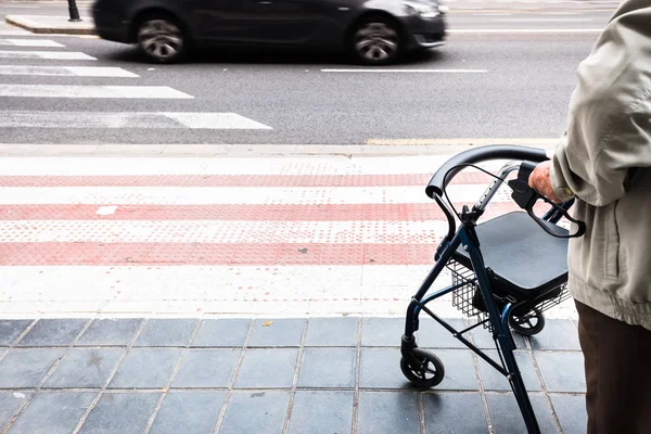 Älterer stützt sich auf Rollator, der die Straße überquert. — Stockfoto