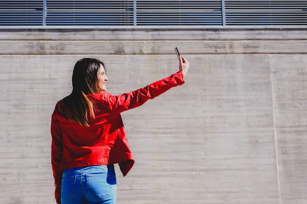 Chica en chaqueta de cuero rojo tomando una foto selfie, con su propia s — Foto de Stock