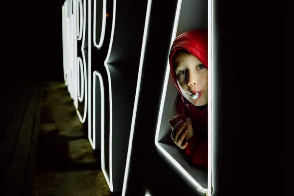 Straszny chłopiec w czerwonym kapturze, ukryty, zjada cukierki. — Zdjęcie stockowe
