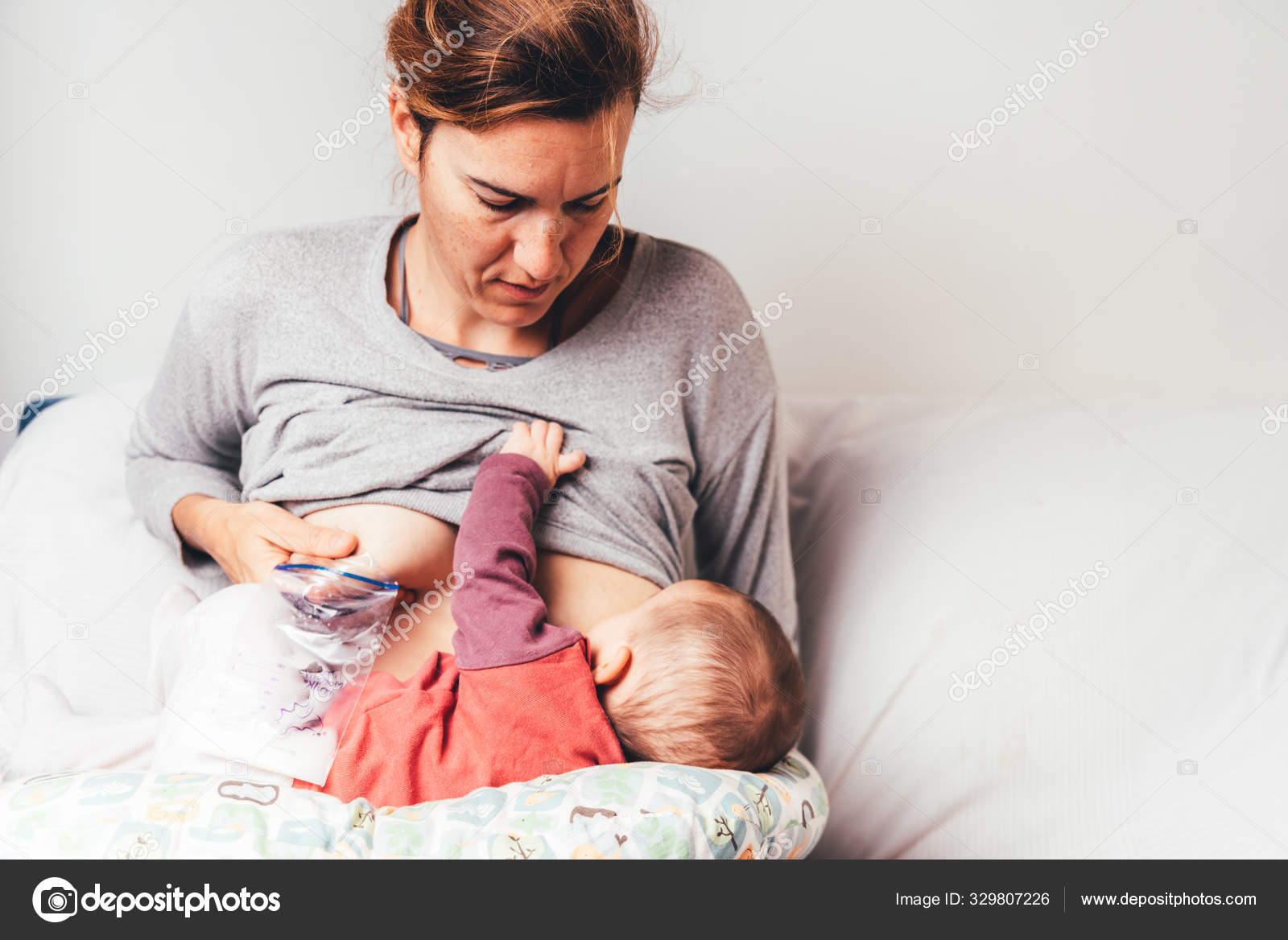 Mother breastfeeding her newborn baby while pumping milk from he