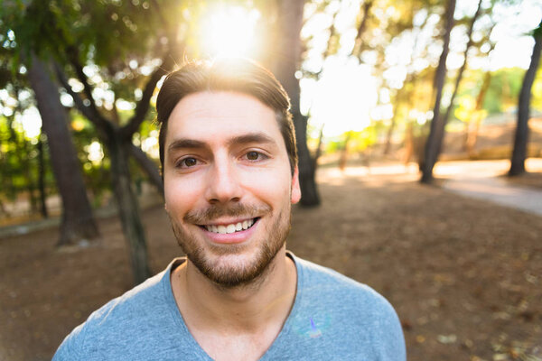 Nice handsome young man posing smiling in a park.