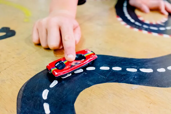 Kind spielt mit zwei Miniaturautos in Spielzeugparcours. — Stockfoto
