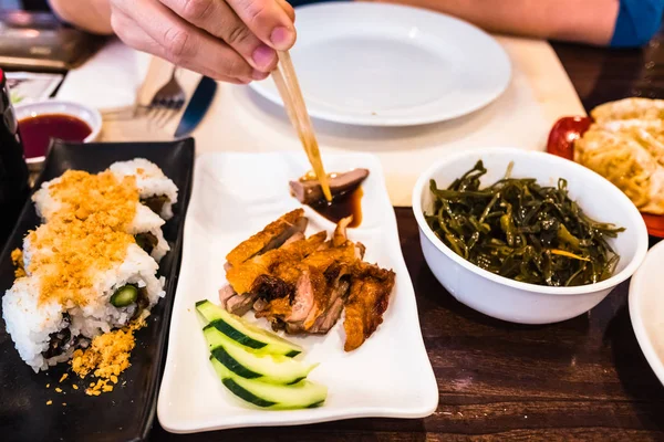 Detalle de varios platos de comida asiática en un restaurante y una chica i — Foto de Stock