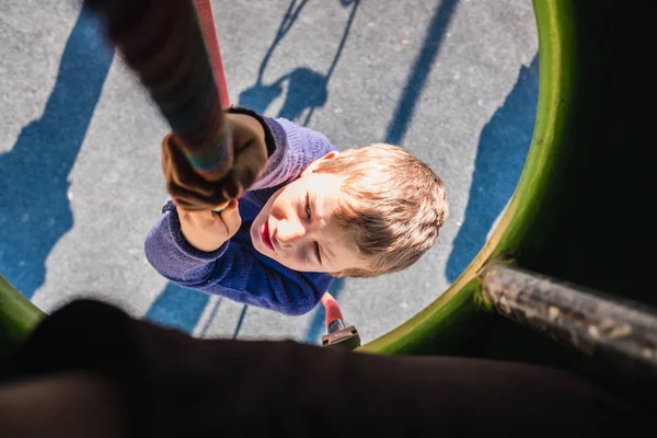 Niño joven aferrado a una cuerda en un patio de juegos de aventura. —  Fotos de Stock