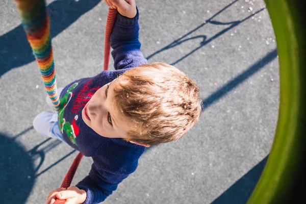 Boy goes down with a rope from a play tower in a park. — Stock Photo, Image