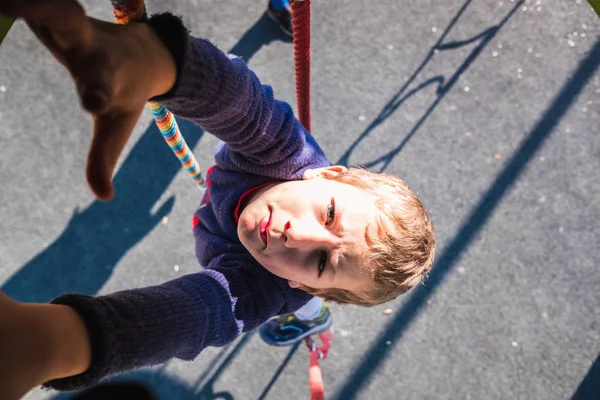 Boy goes down with a rope from a play tower in a park. — Stock Photo, Image