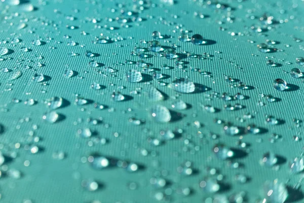 Primer plano de gotas de lluvia naturales y refrescantes en el tejido de un — Foto de Stock