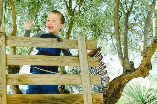 Kind winkt vergnügt auf dem hölzernen Baum — Stockfoto