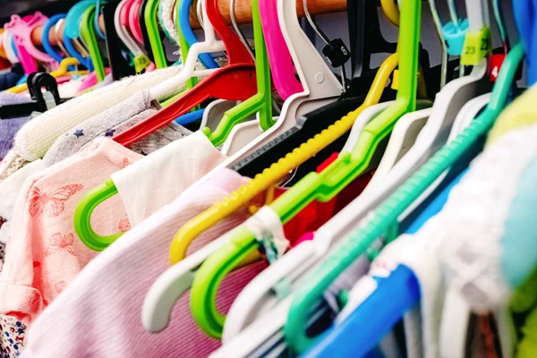 Colorful children's dresses hanging on hangers in a closet. Stock Photo
