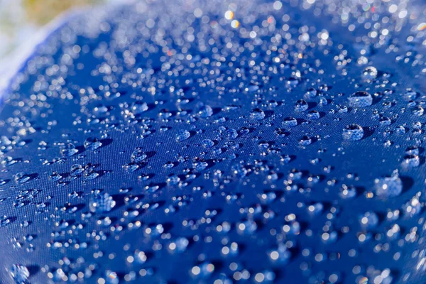 Detalle de gotas de agua sobre una tela plástica coloreada al sol . — Foto de Stock