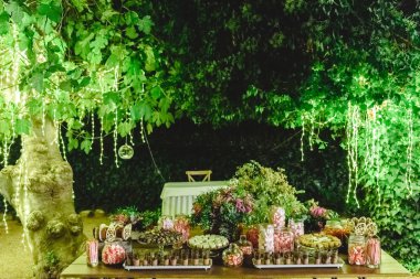 L ile aydınlatılmış gece bir bahçede tatlı tatlılar ile Tablo