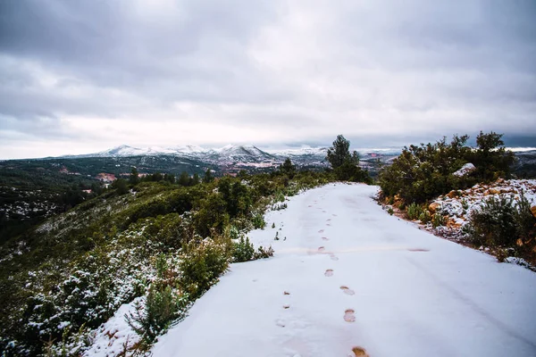 Paisagem nevada com passos sobre a neve da estrada da montanha — Fotografia de Stock