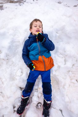 Young boy lying in the snow  happy