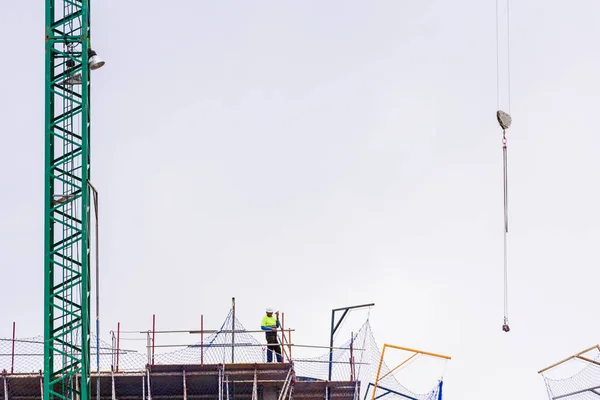 クレーンを指揮する建築物の上に建設労働者 — ストック写真