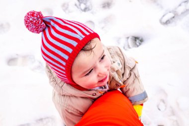 Adorable little girl with snow cap playing hugging her funny fat