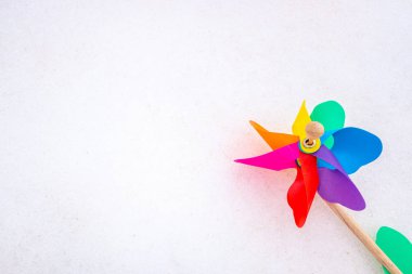 Colorful pinwheel on snow, isolated white background.