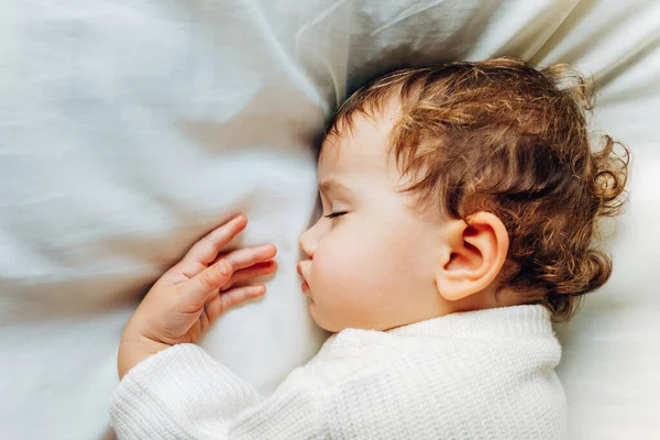 Baby sleeps peacefully during a nap at noon lying on a fluffy wh — Stock Photo, Image