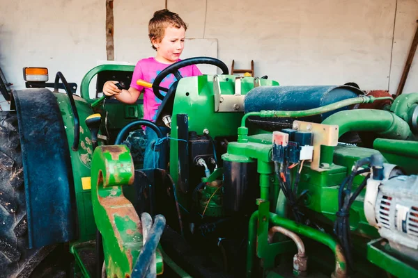 Băiat cu cămașă roz pe un tractor de fermă jucând pentru a fi fermier, ge — Fotografie, imagine de stoc