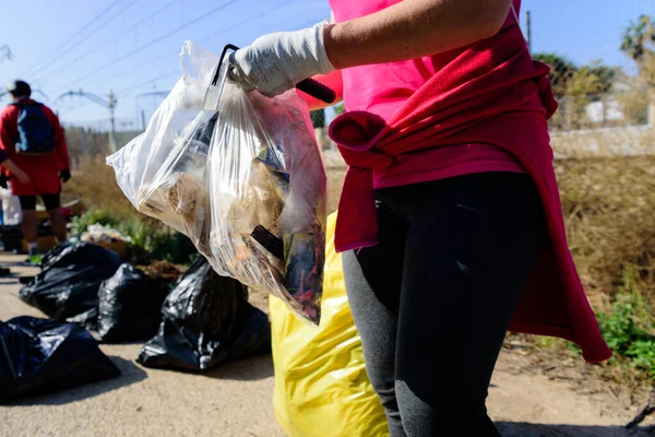 Voluntarios recogen basura plástica de un contaminado e natural — Foto de Stock