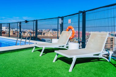 A swimming pool with sun beds on the roof of a building in the c