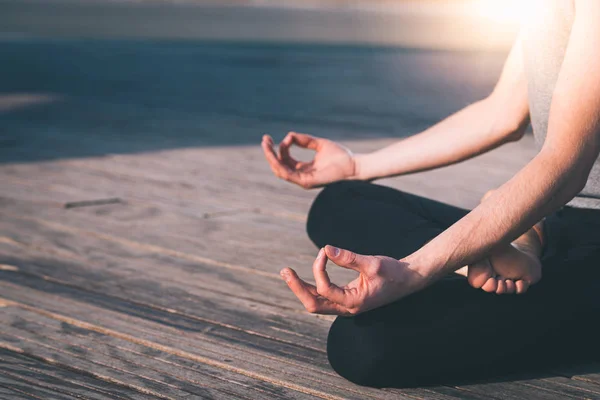 Detail of the hands of a young man who meditates practicing yoga