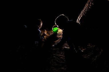 Bir grup çocuk, gece boyunca kum havuzunda oynuyorlar.