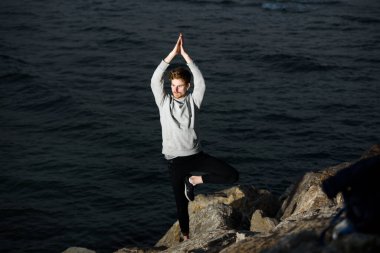 Yoga yapan genç kızıl saçlı, Vriksasana ağaç duruşu. Konsantre olmak ve farkındalığında ona yardım etmek için.