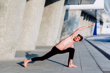 Genç erkek sporcu şehir merkezinde sırt ve kollar için esneme egzersizleri yapıyor..
