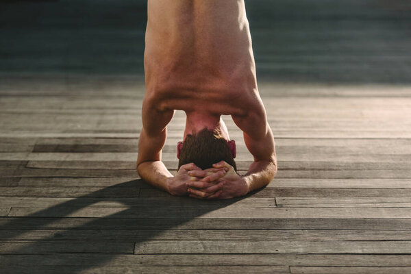 Yoga apprentice practicing sirsasana, inverted posture with the head resting on the floor.