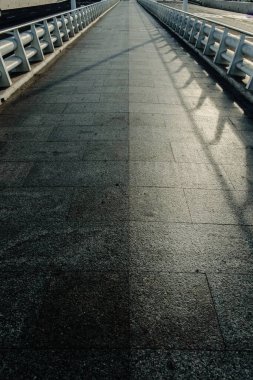 Ufukta kaybolma çizgisi olan beyaz metal korkuluklu uzun mermer bir fayans yolu. Kimsesiz, sadece yön kavramı..