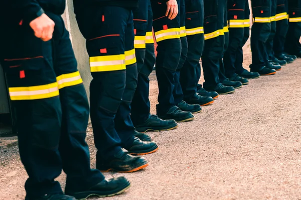 许多面目全非的消防员穿着反光裤排成一排 — 图库照片