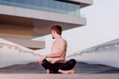 Guru yogası nilüfer pozisyonunda oturarak çıplak gövdesini geriyor..