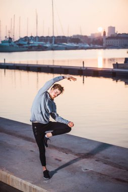 Genç sporcular yoga yapıyor, ellerinde ağaç duruşu var, Vrksasana..