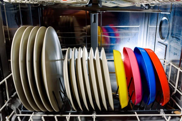 Clean dishes and cutlery inside a dishwasher at home.