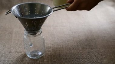 Kefir sütünün ev yapımı hazırlığı, granülleri süzgeçle ayırmak ve probiyotiklerle dolu doğal bir yoğurt hazırlamak.