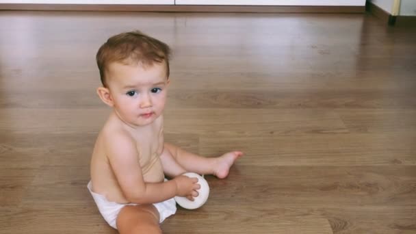 床に座っている赤ん坊は 奇妙な方法でカメラの前で笑顔と笑いを再生し フィルム穀物を追加しました — ストック動画