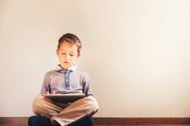 Bir tablet içinde absorbe kullanma katta oturan çocuk.