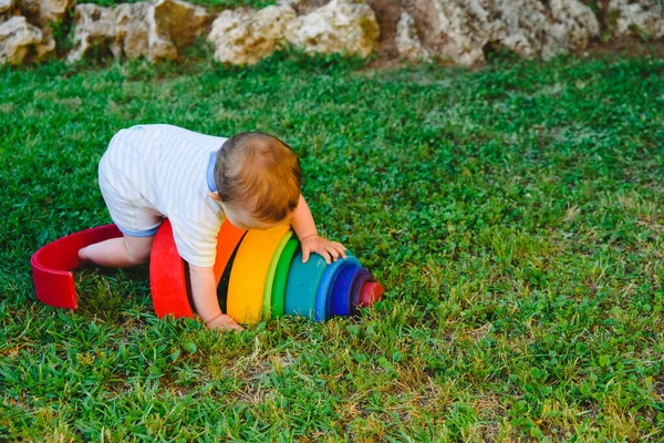 Baby Spielt Mit Einem Bunten Hölzernen Regenbogen Auf Dem Rasen — Stockfoto